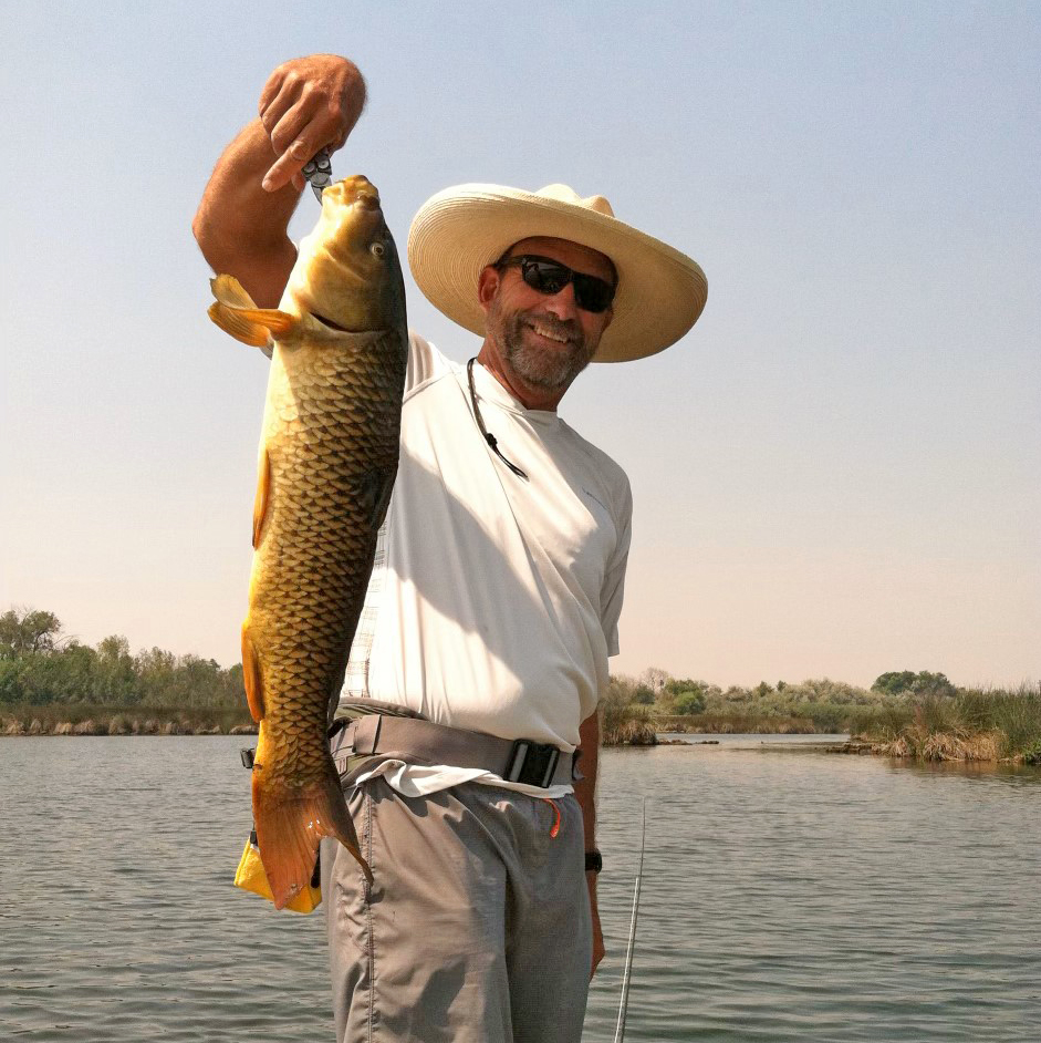 Fly angler with a large common carp.
