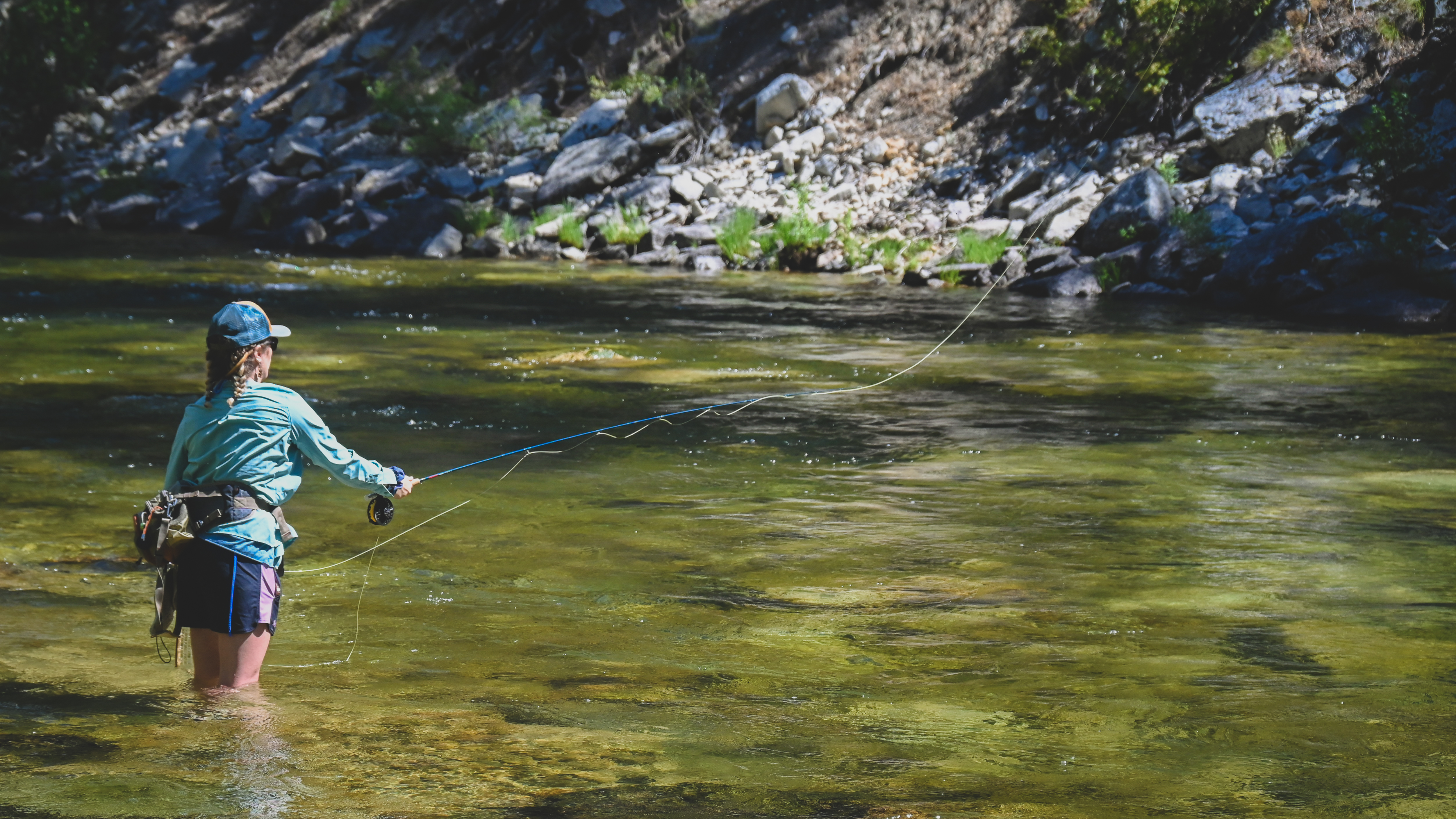 woman fly fishing in summer along mountain river