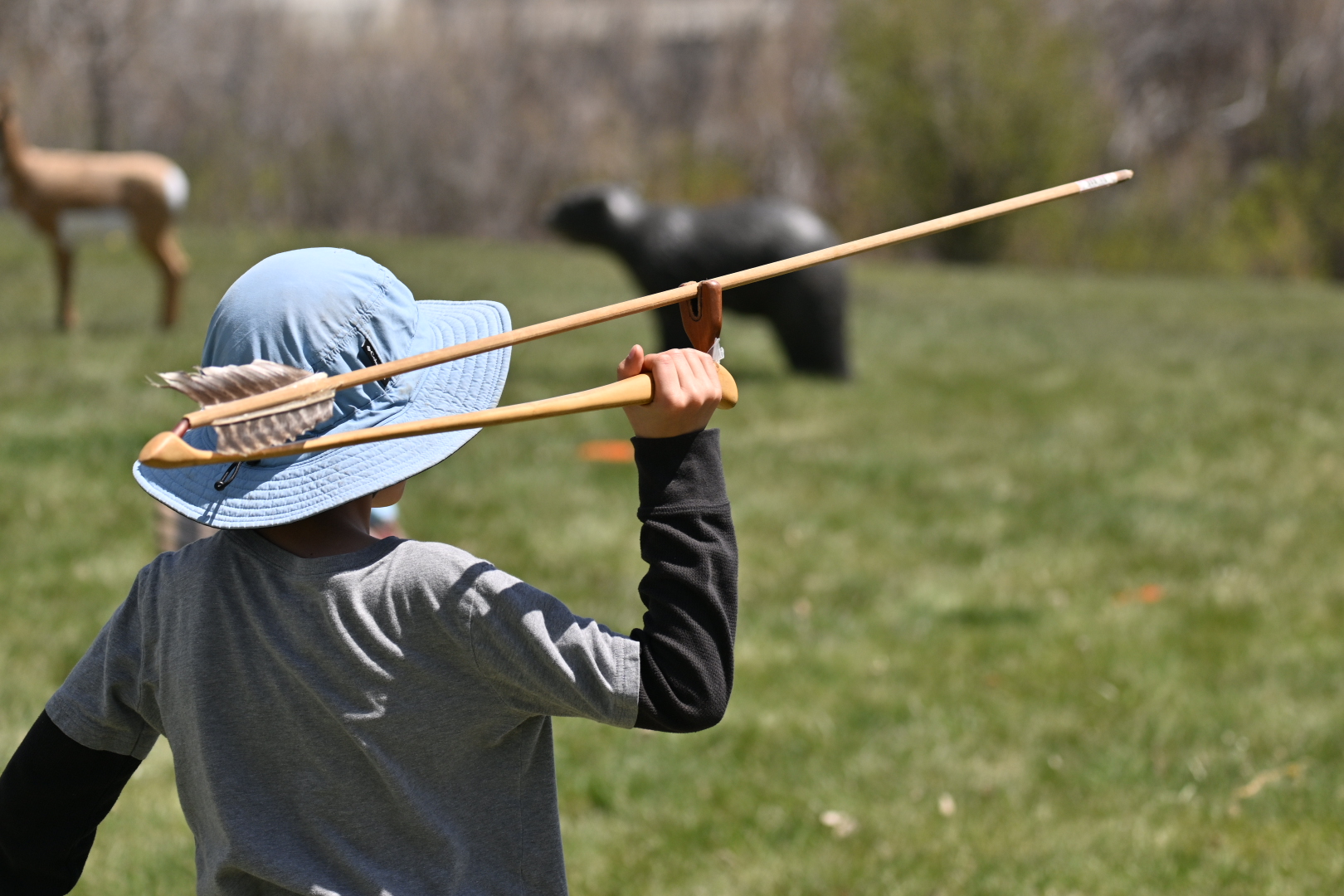 child throwing an atlatl dart at an archery target