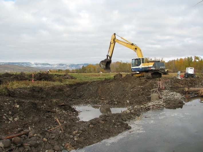 An excavator works to cut a new river channel in the earth