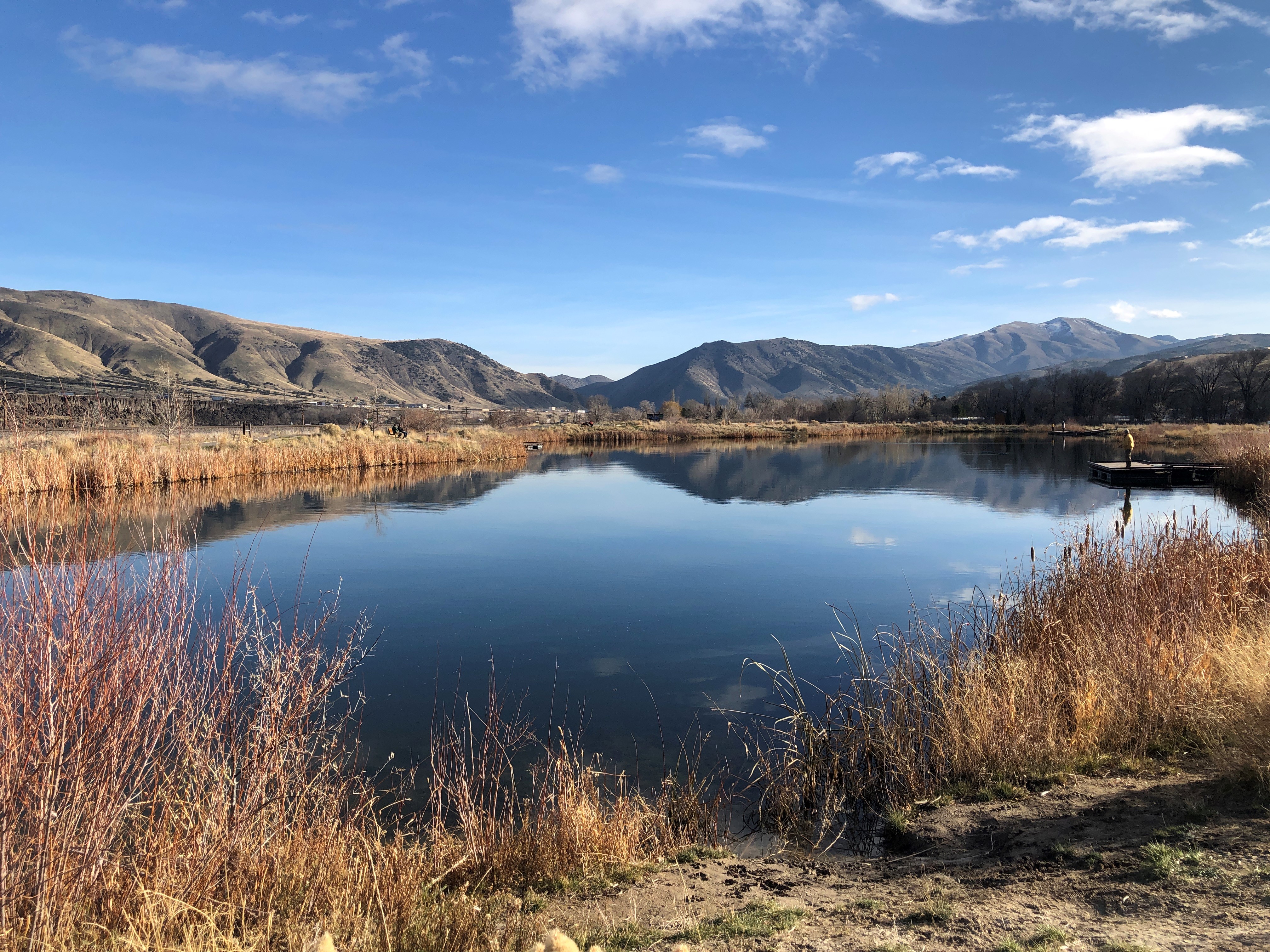 A blue fishing pond sits under a blue fall sky.