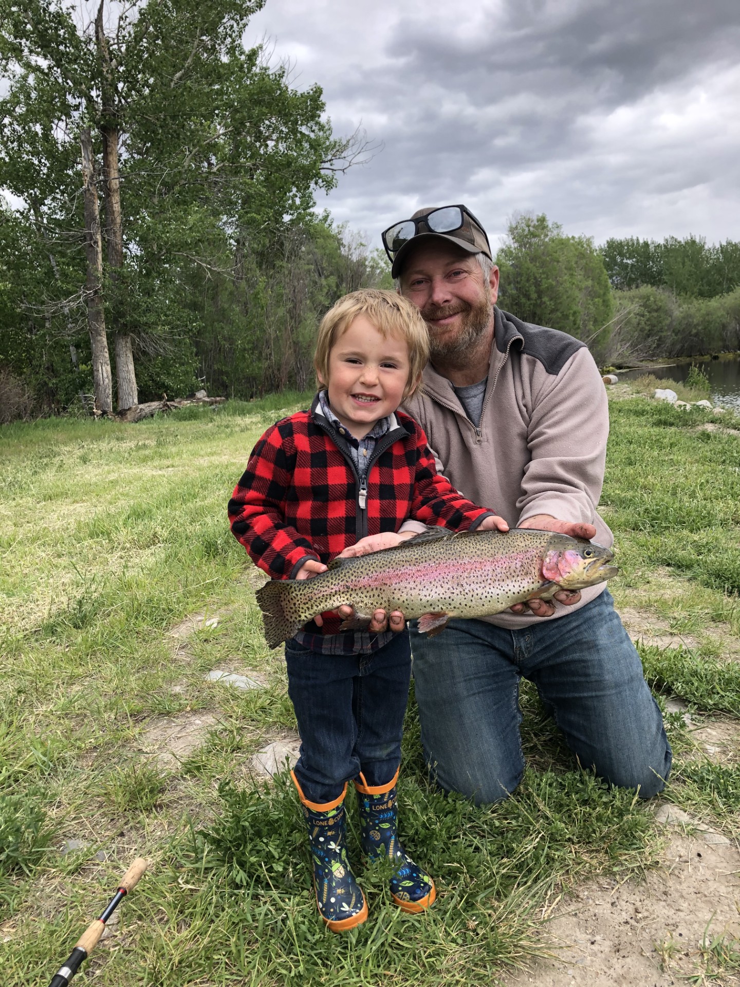 Father and son showing off a large rainbow trout