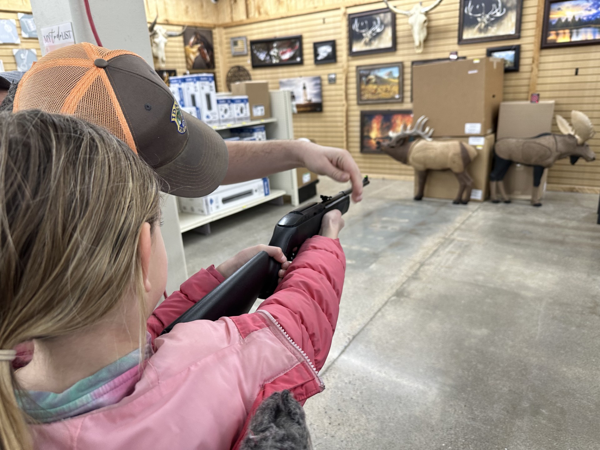 Male shooting instructor showing young girl how to properly hold a "dummy" hunting gun for practice