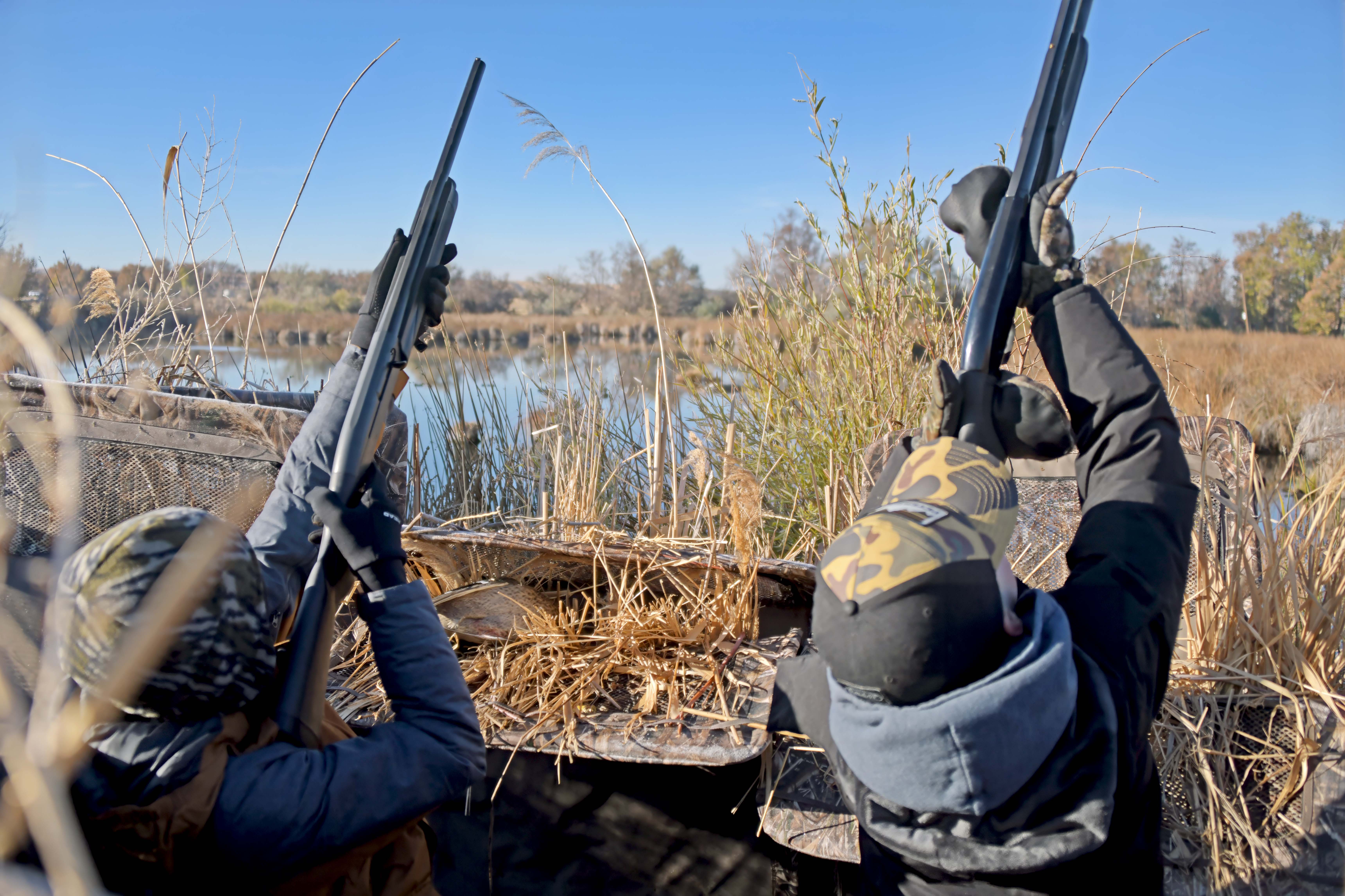 Two young boys pulling up on flying ducks at the mentored youth duck hunt Hagerman WMA