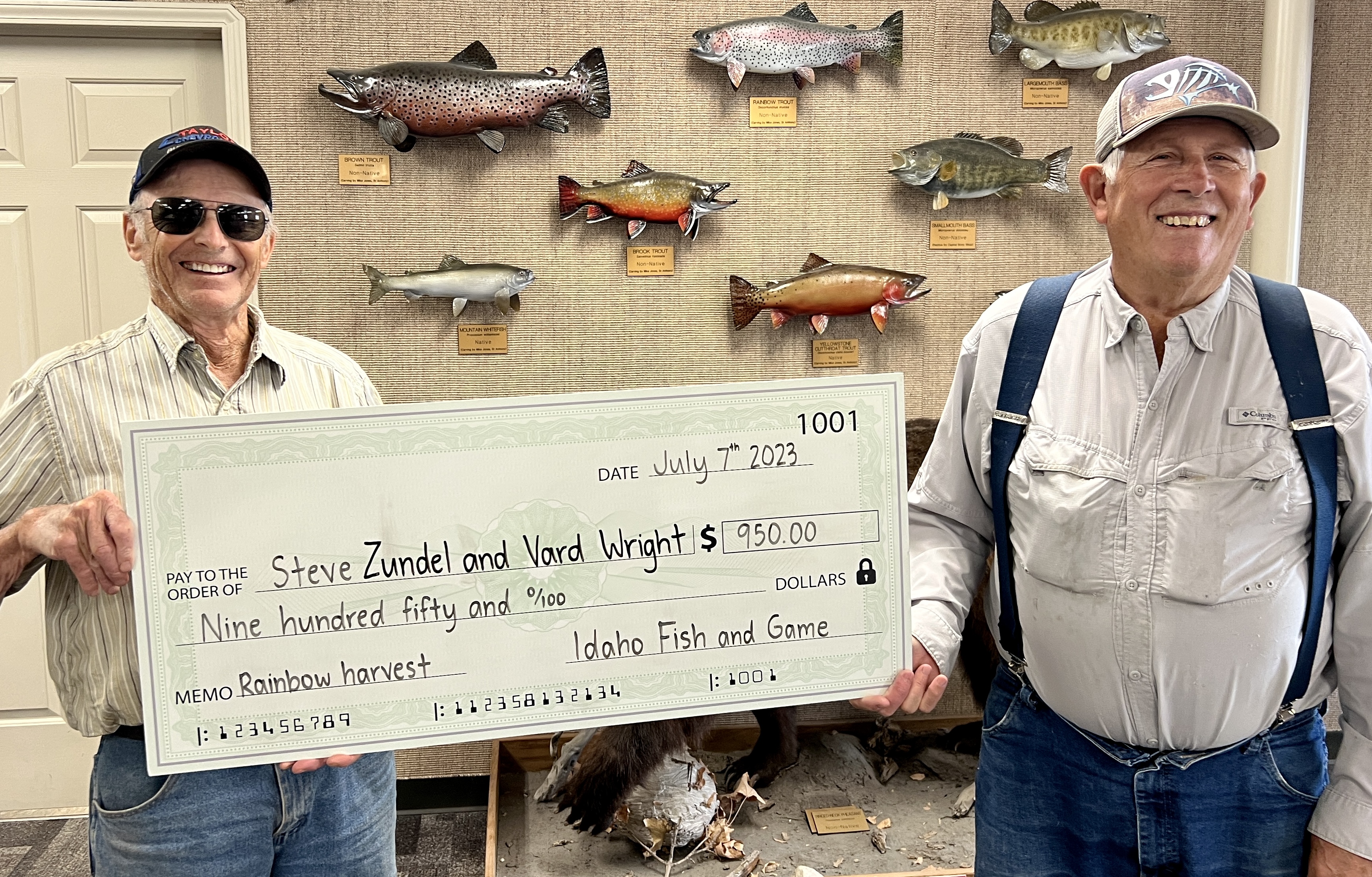 Two anglers holding a $950 check for harvesting rainbows