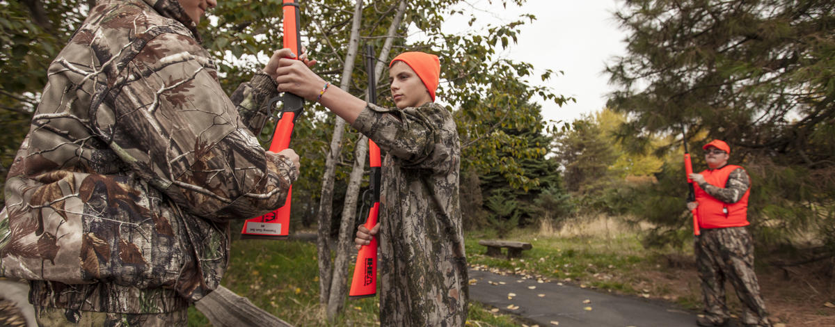 two girls passing rifles over a fence during a hunter education class October 2015