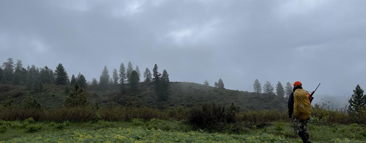 big_game_hunter_with_rifle_hiking_in_wet_weather_1699