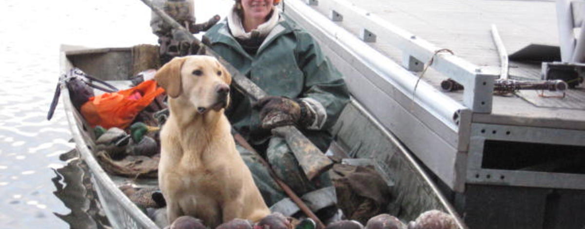 hunter showing off her ducks with a dog in a boat on the Coeurd' alene River November 2010