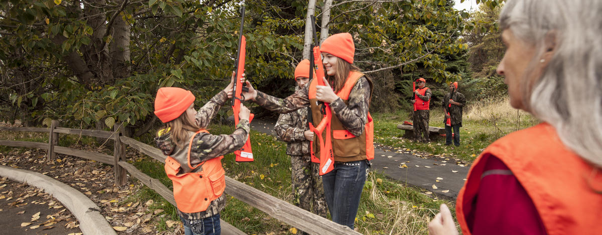 girls learning how to cross a fence with rifles on hunter education field day October 2015 