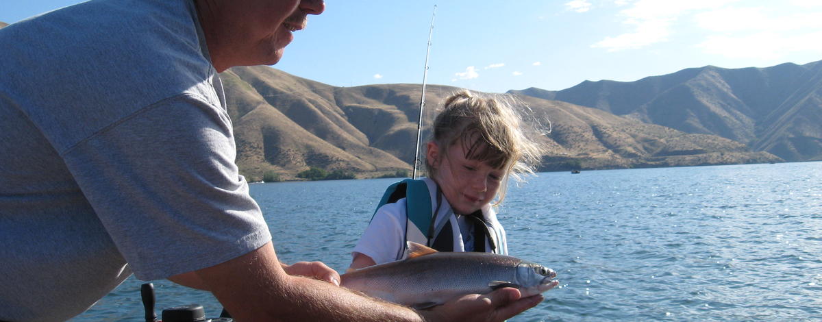 A girl poses with a kokanee she caught in Southwest Idaho