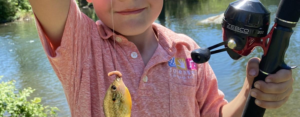 Young child with a fish caught at a Panhandle Take Me Fishing! trailer event