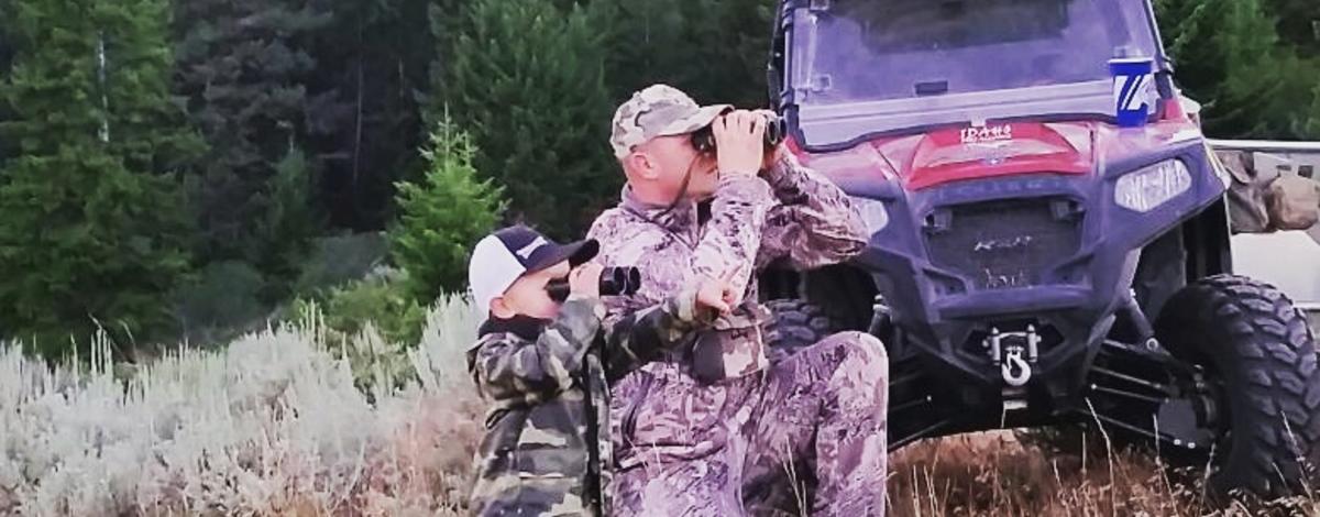 dad and son hunting and using binoculars looking for game 