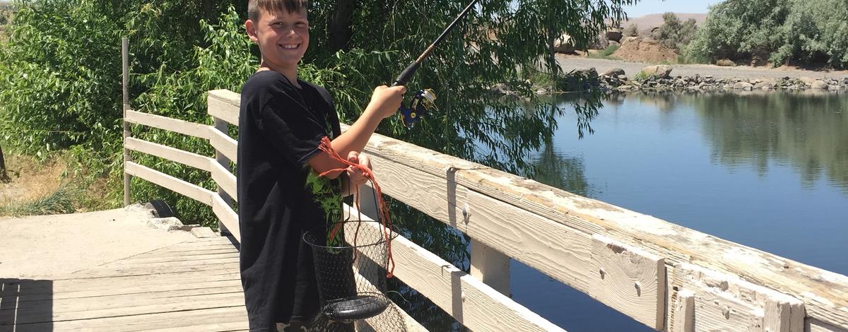 boy fishing from a bridge at Hagerman ponds medium shot June 2015
