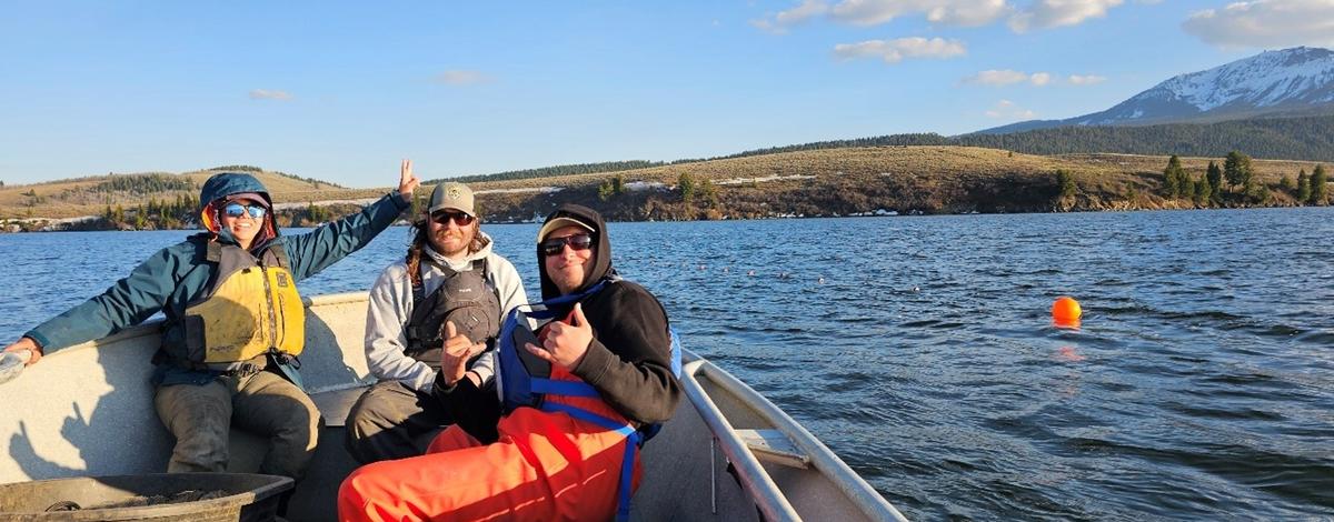 3 fisheries technicians sitting on the bow of a boat on Henrys Lake