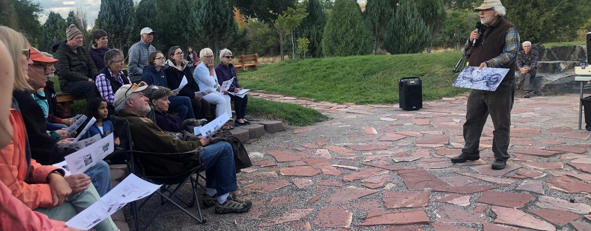 people watching a presenter standing in an outdoor amphitheater