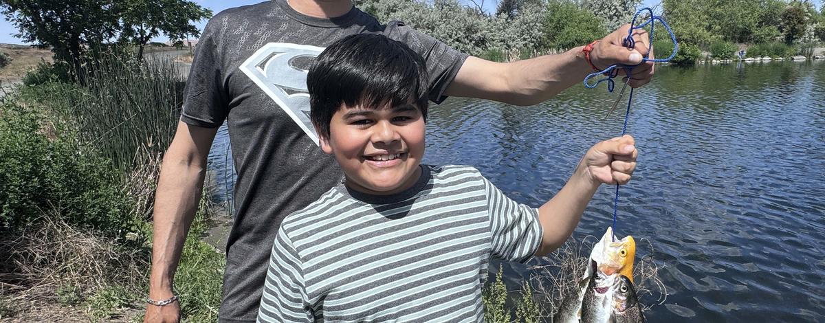 A young boy catches trout at Free Fishing Day at Riley Pond in Hagerman