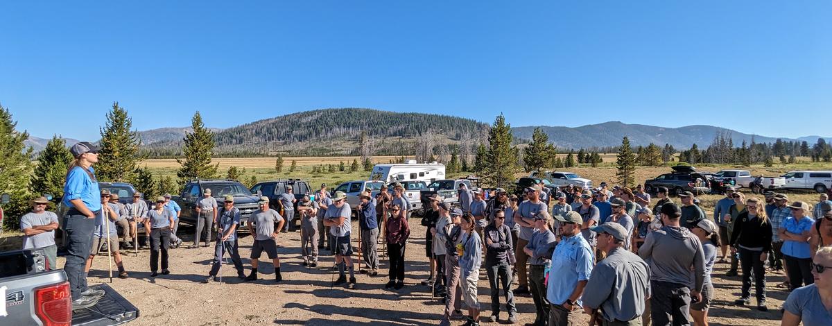 A large group of fisheries professionals gather around Carli Baum who explains details on how to identify salmon redds