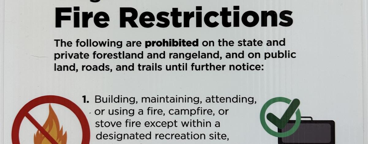 a white sign with large black lettering warns of stage 1 fire restrictions