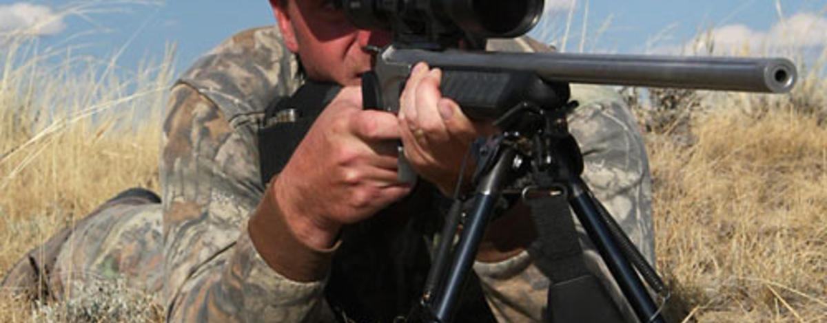 hunter shooter taking aim with his rifle and scope wearing a hunter orange cap April 2014