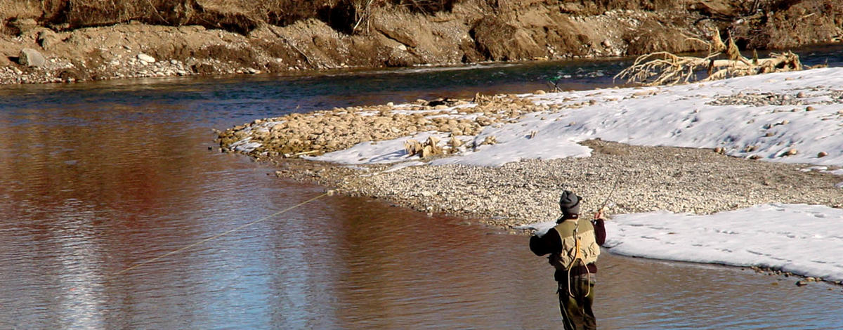 tight shot of an angler fishing on the South Fork of the Snake river in the Winter with snow on the river bank