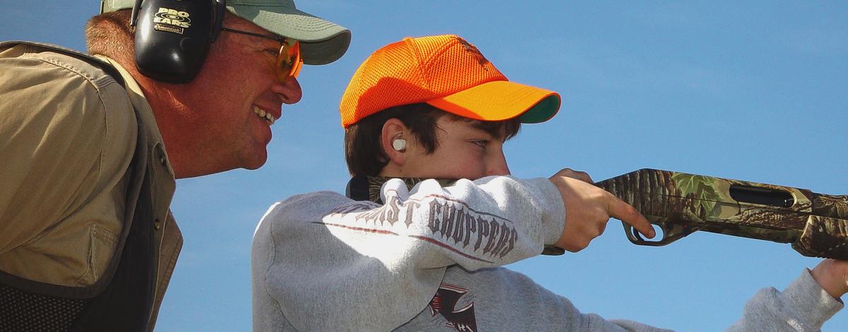 an instructor watches as a boy fires a rifle at a youth pheasant hunt November 2004