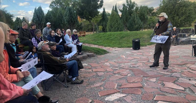 people watching a presenter standing in an outdoor amphitheater