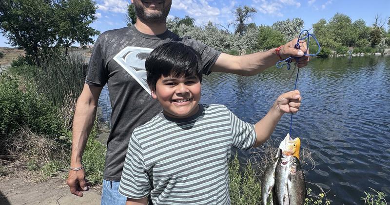 A young boy catches trout at Free Fishing Day at Riley Pond in Hagerman