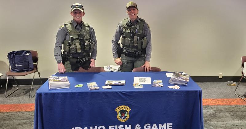 Two female conservation officers stand at a booth