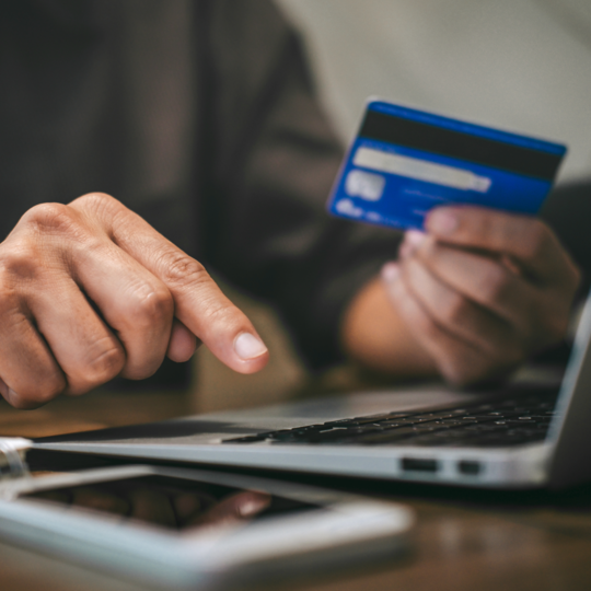 Using a laptop, a person makes a payment using a credit card