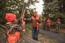 two girls passing rifles over a fence during a hunter education class October 2015