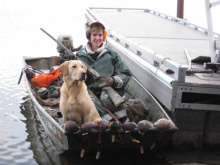 hunter showing off her ducks with a dog in a boat on the Coeurd' alene River November 2010