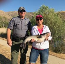 Conservation Officer Craig Mickelson helps angler Tammy Thomas reel in a large catfish at Horseshoe Bend Pond in 2018