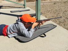 boy wearing a hunter orange cap learning how to fire a rifle during a Hunter Education class August 2016