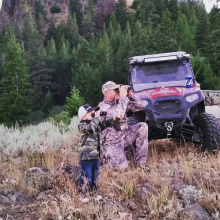 dad and son hunting and using binoculars looking for game 