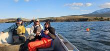 3 fisheries technicians sitting on the bow of a boat on Henrys Lake