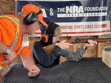 Hunter education instructor assisting student with live fire