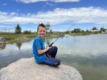Smiling child fishing from a rock