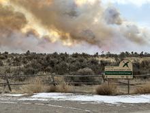 Smoke rises above sagebrush landscape during a prescribed fire.  Sterling WMA sign in foregroud.