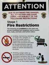 a white sign with large black lettering warns of stage 1 fire restrictions