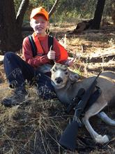 boy with is mule deer buck and rifle in hunter orange vertical shot