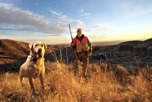 medium portrait shot of a hunter in hunter orange and his dog in autumn Fall