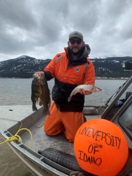 Bryce Marciniak poses with perch in front of University of Idaho buoys on Lake Cascade